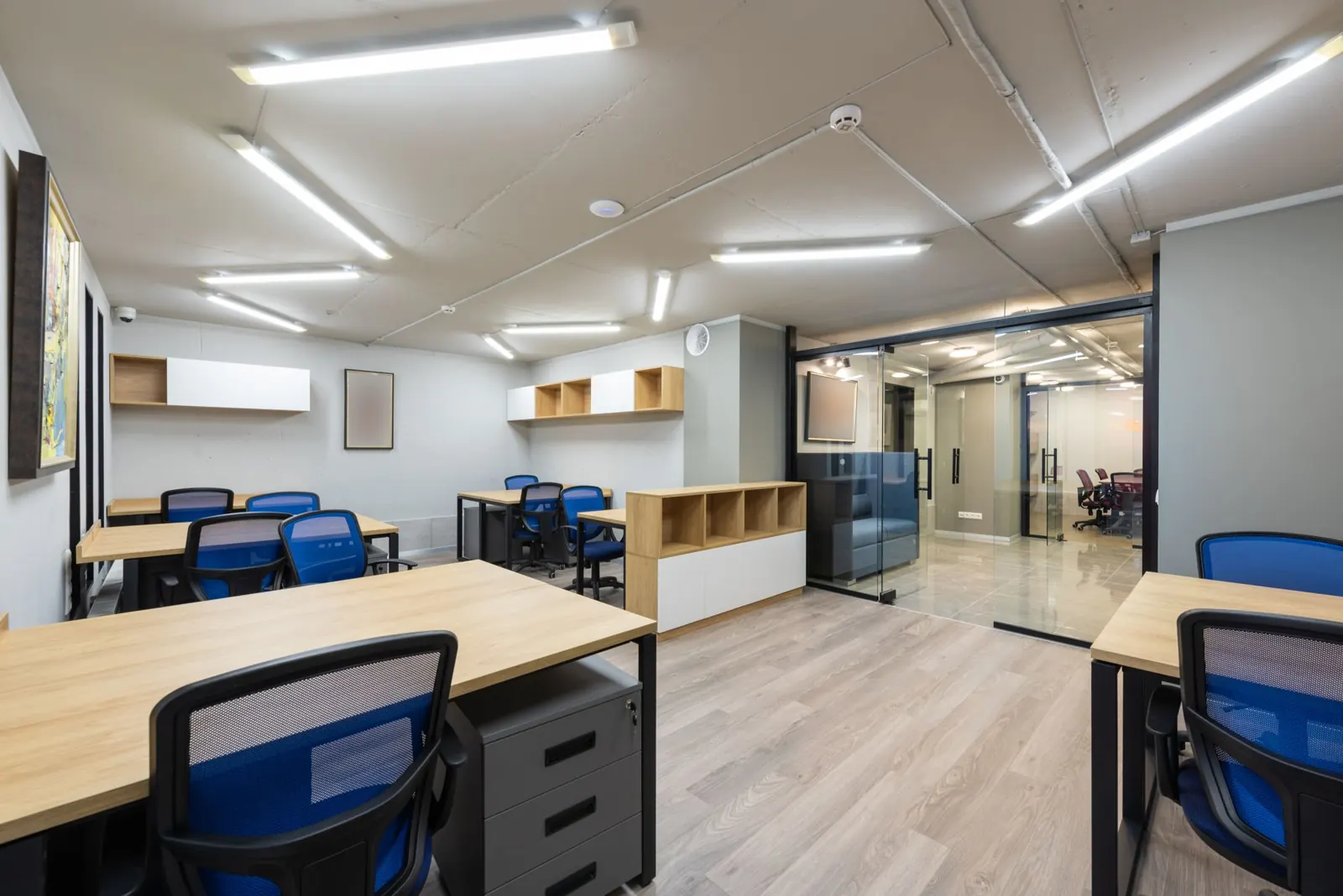 Bright, tidy office with desks, blue chairs and glass doors