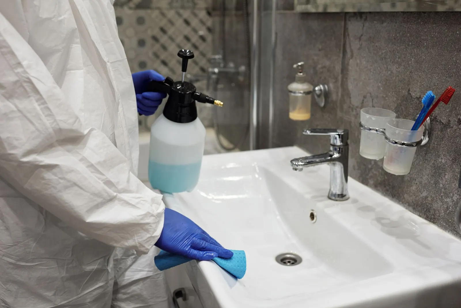 Bathroom sink being sprayed and scrubbed during a deep clean
