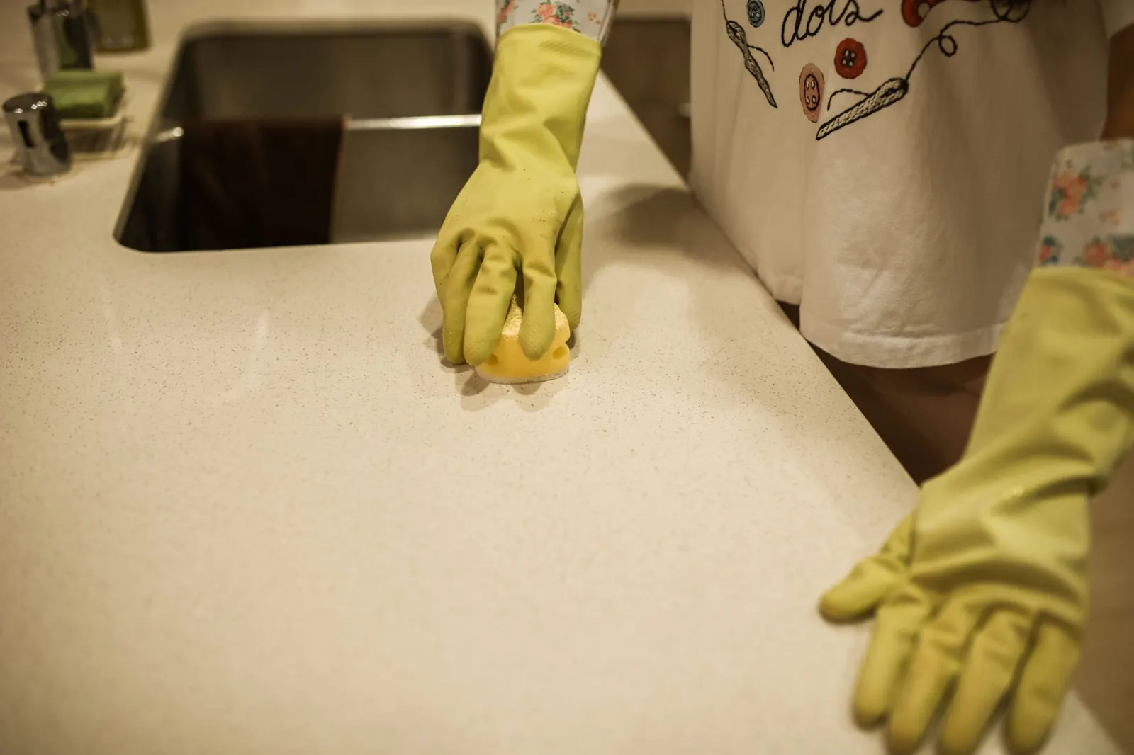 Gloved hands wiping a kitchen counter clean