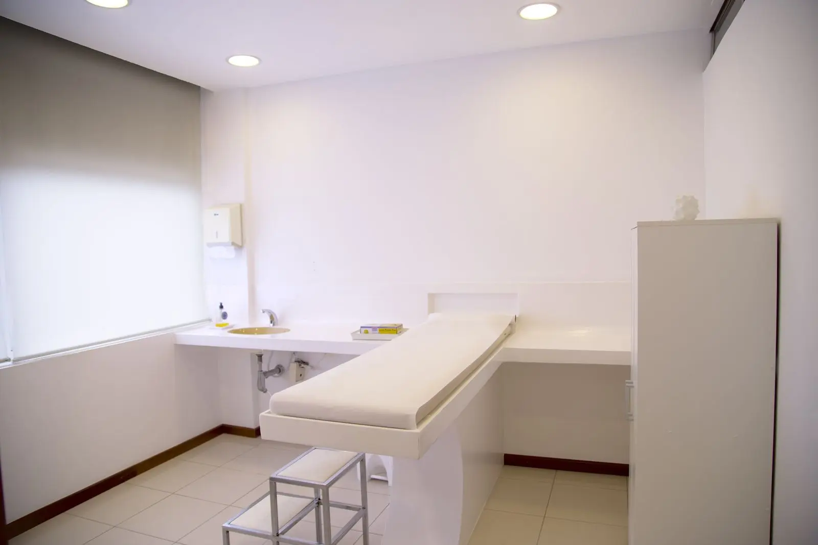 Bright, clean exam room with a treatment table, sink and cabinet